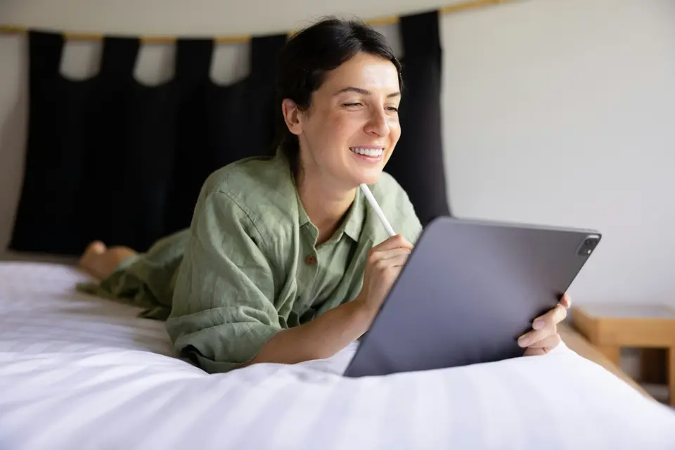Person reviewing wellness information on a laptop while seated on a bed.