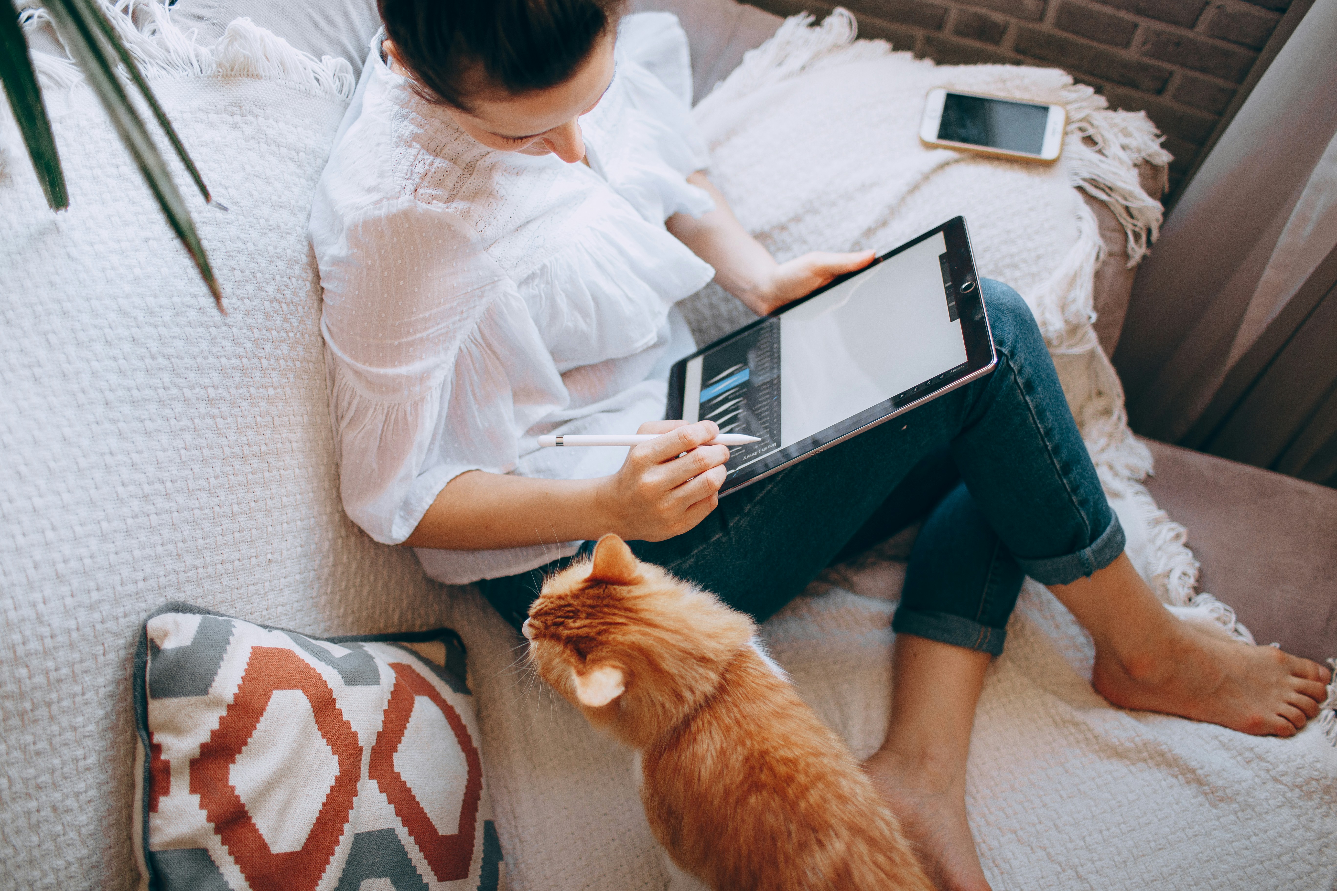 Woman using a tablet at home with her cat.